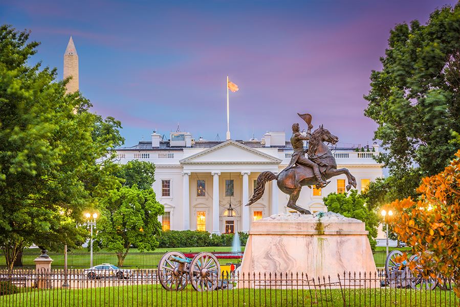 The White House with a bronze statue in the foreground and the Washington Monument in the background.